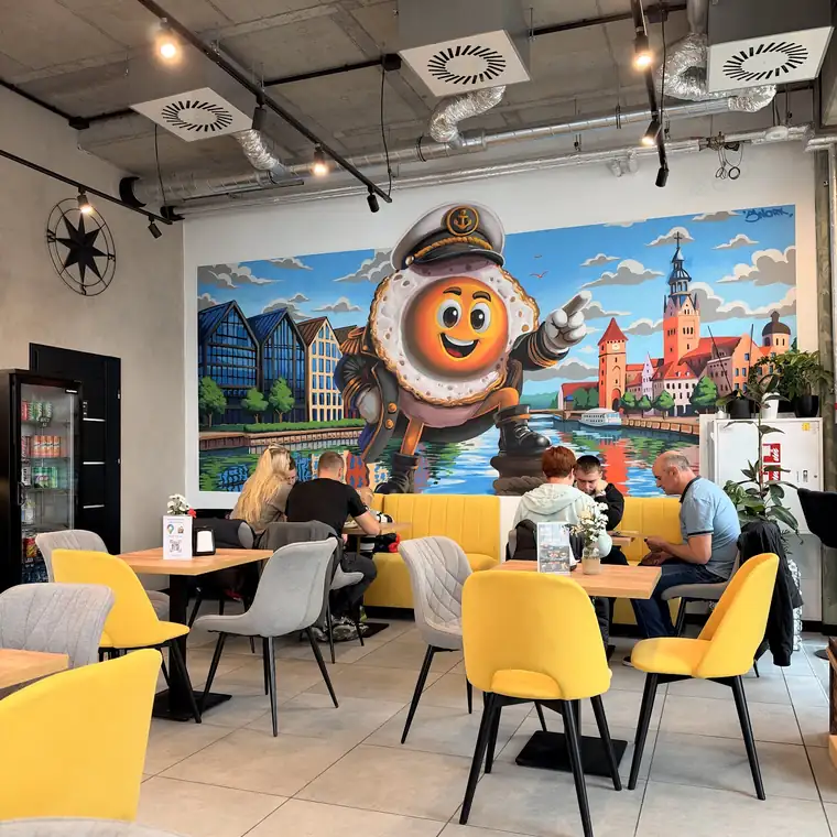 Sala z muralem jajka-kapitana i żółtymi krzesłami